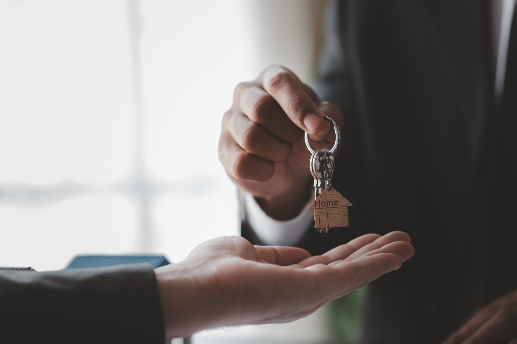 A home rental company employee is handing the house keys to a customer who has agreed to sign a rent