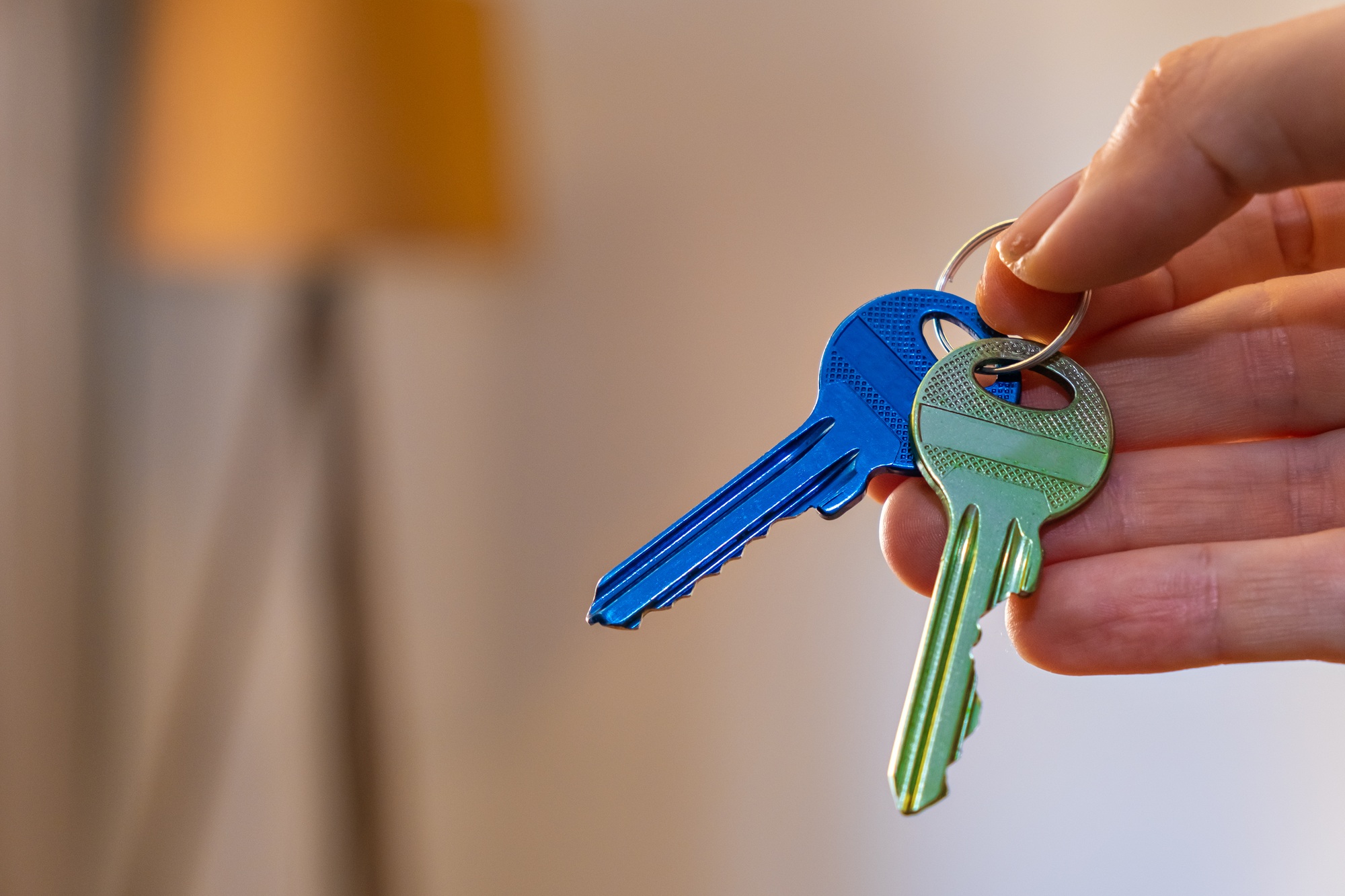 hand holding keys with room on background. rent sell buy apartment real estate business